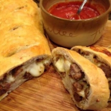 Three Slices of Italian Sausage Bread Next to a Bowl of Marinara Sauce